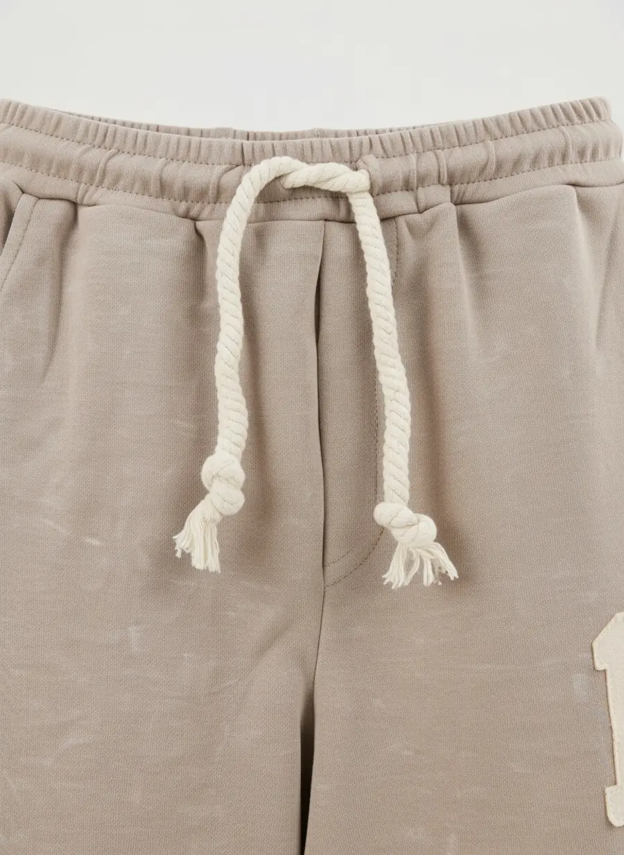 Close up of a thick cotton drawcord and its knotted ends on a pair of sand coloured sweatpants