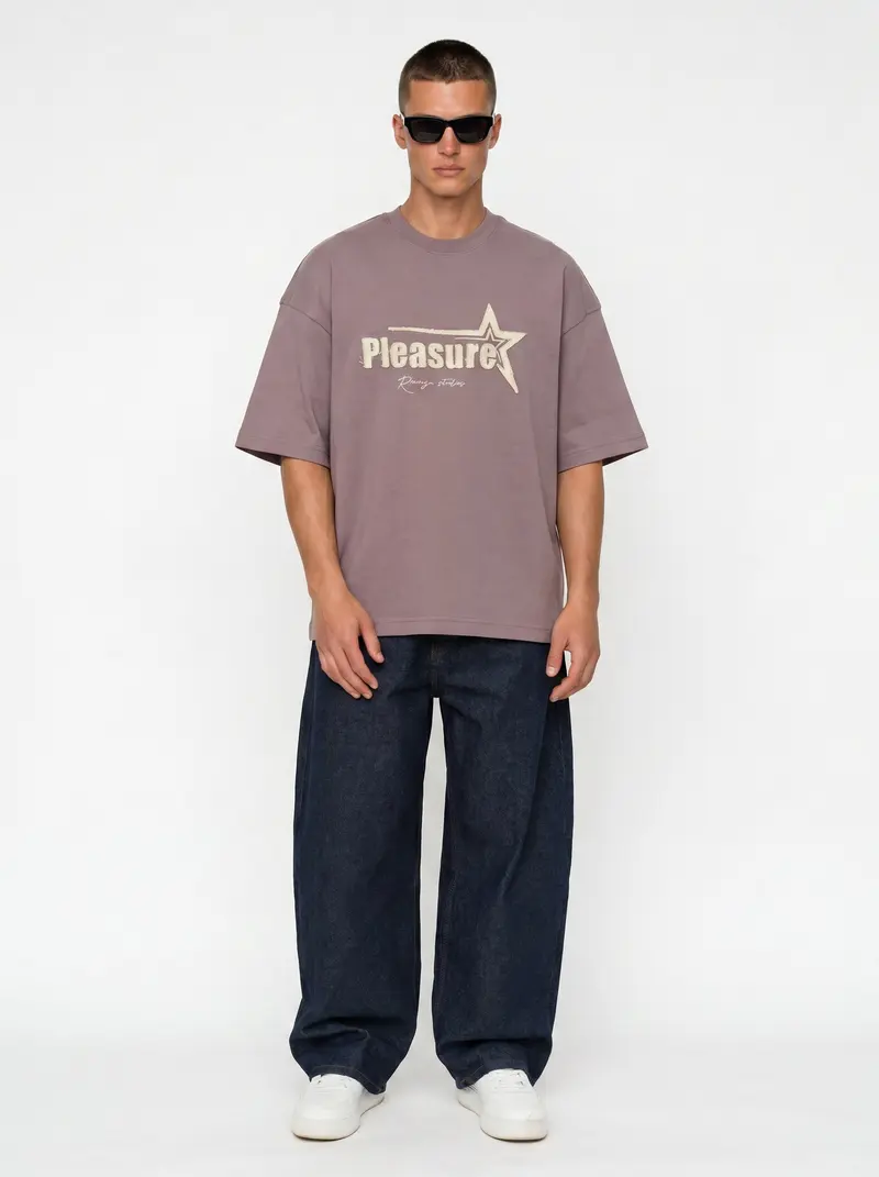 Bully Pleasure Star Tee in mauve on the same male model in black sunglasses in a white studio, posed differently from the other colourways