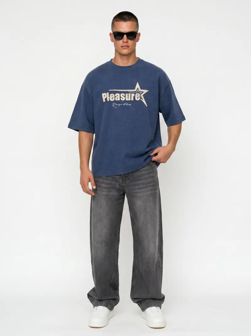 Bully Pleasure Star Tee in navy on the same male model in black sunglasses in a white studio, posed differently from the other colourways
