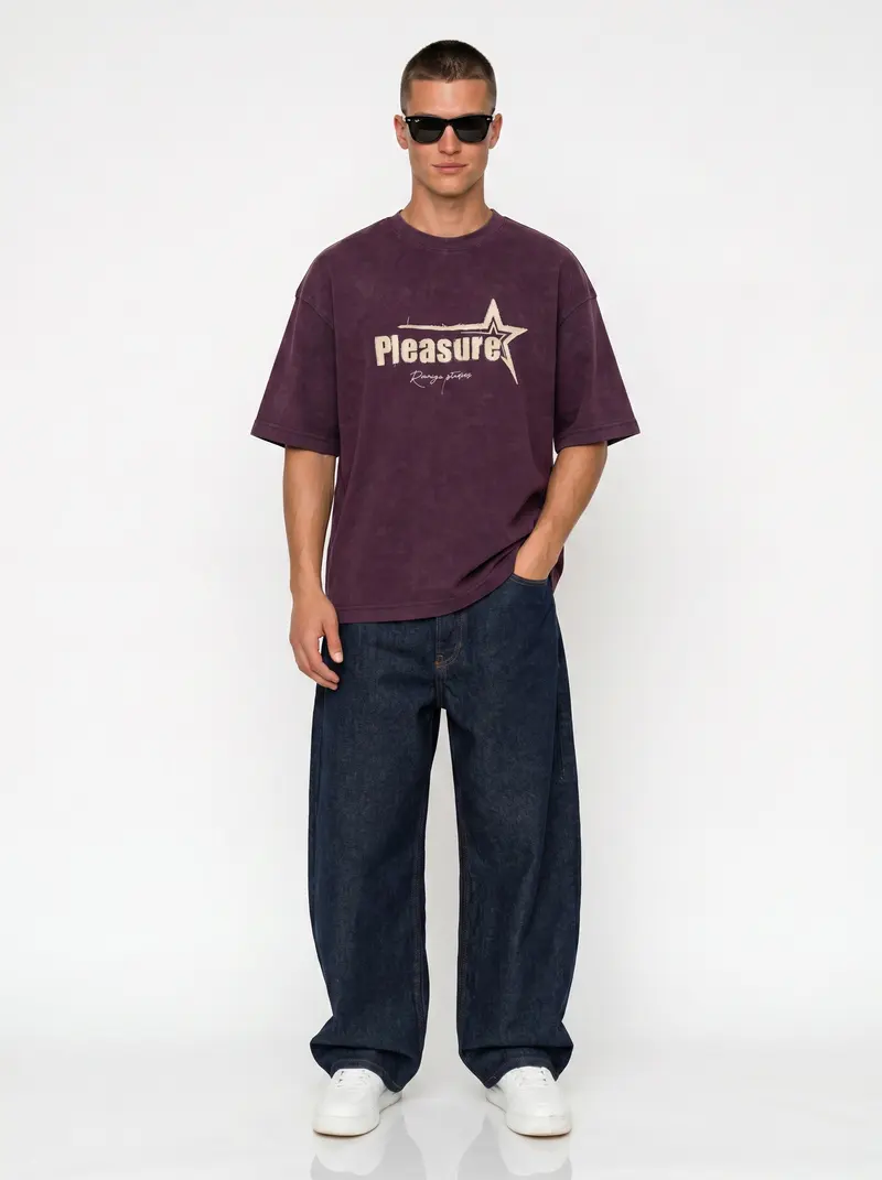 Bully Pleasure Star Tee in plum on the same male model in black sunglasses in a white studio, posed differently from the other colourways