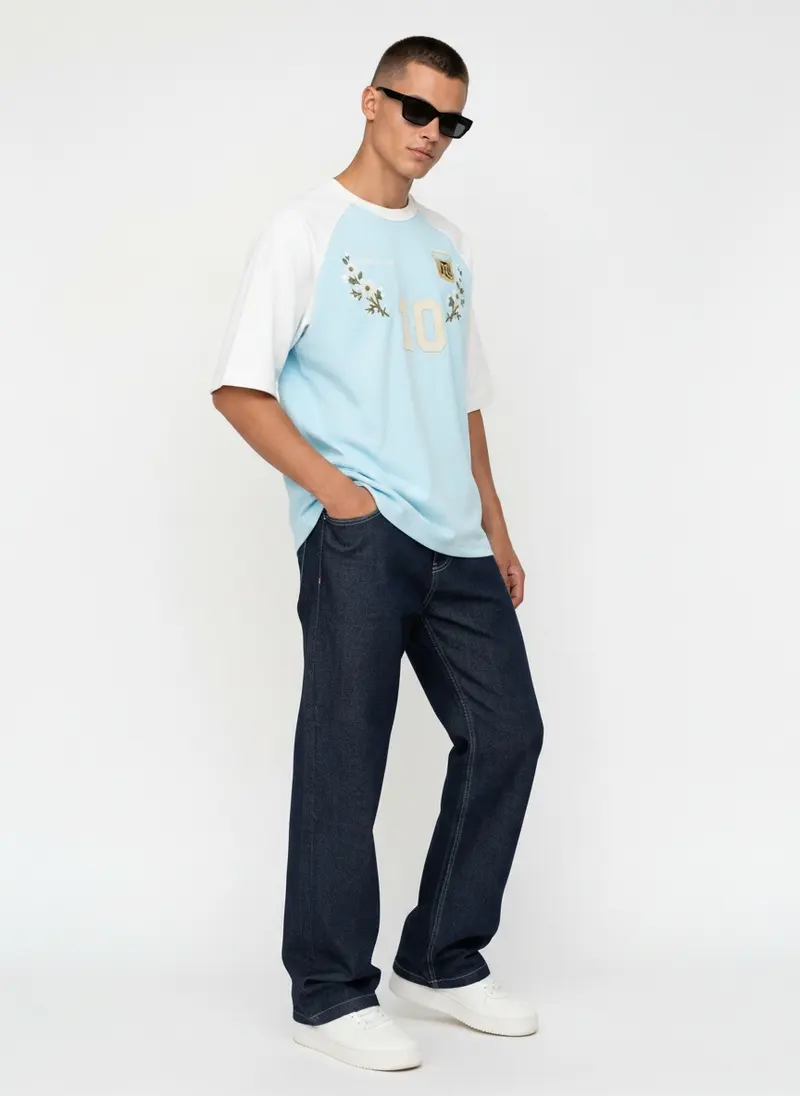 Bully Essence Club Raglan in sky on the same male model in black sunglasses in a white studio, posed differently from the other colourways