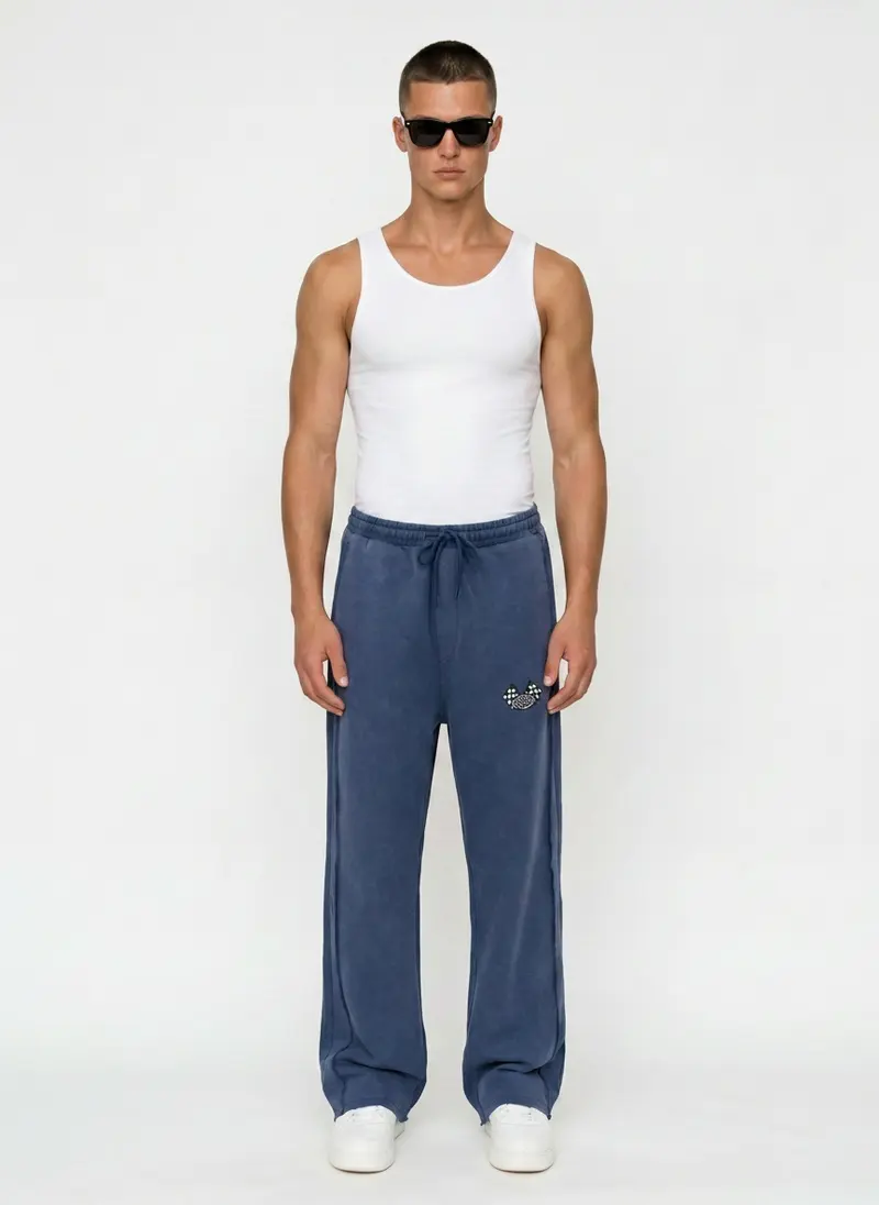 Bully Bully Sweatpant in denim blue on the same male model in black sunglasses in a white studio, posed differently from the other colourways