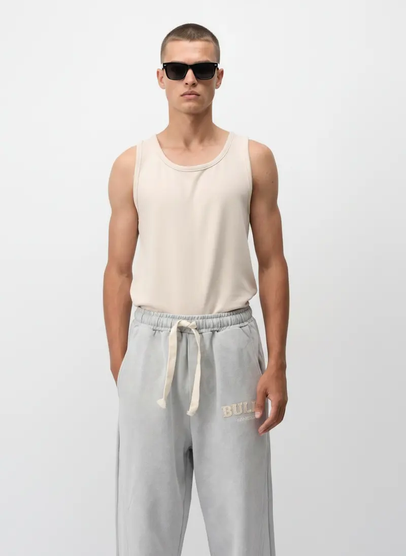 Bully Bully Sweatpant in grey on the same male model in black sunglasses in a white studio, posed differently from the other colourways