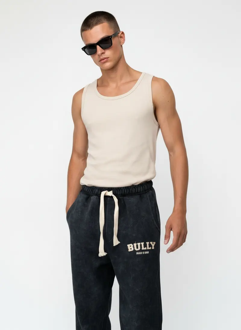 Bully Bully Sweatpant in ink on the same male model in black sunglasses in a white studio, posed differently from the other colourways