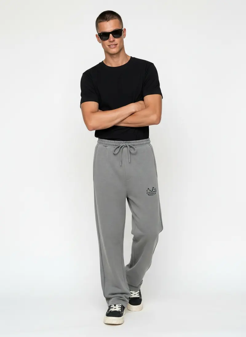 Bully Bully Sweatpant in light grey on the same male model in black sunglasses in a white studio, posed differently from the other colourways