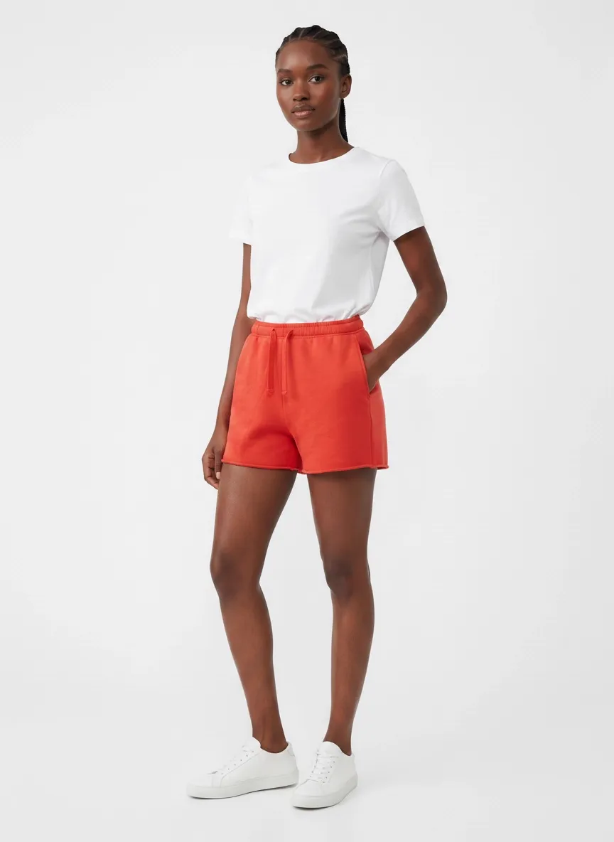 MODA AI catalog output — Black model in white tee and red sweat shorts, three-quarter view with hand in pocket, clean studio backdrop
