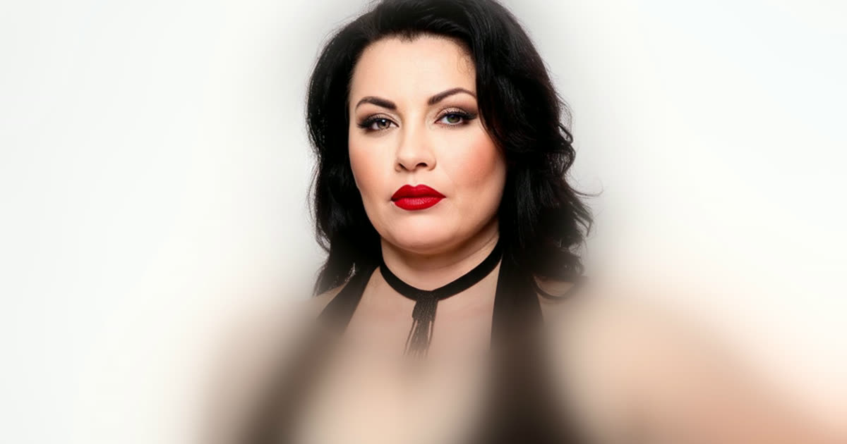 A plus-size model in her late forties with red lipstick and a beaded choker, face in focus and her corset outfit softly blurred