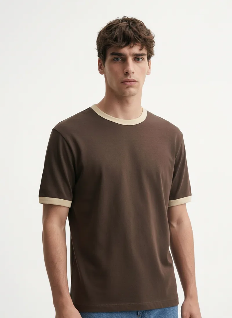 MODA AI output — model in the brown tee tucked into belted jeans, seated, belt visible at the waist