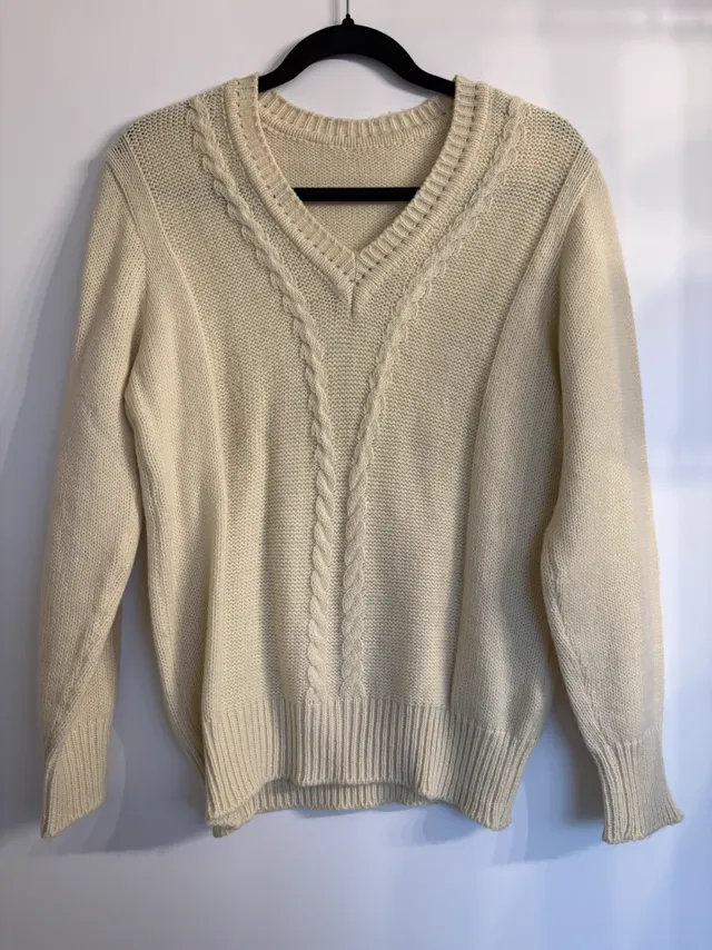 A cream cable knit jumper on a hanger against a curtain, a phone photo used as the input for the knit set