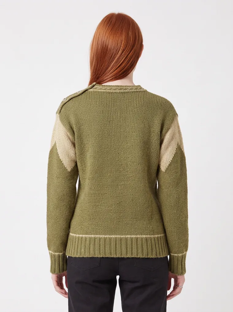 An olive crew-neck knit with tan contrast shoulder panels and cream tipping at the neck and cuffs, worn with black trousers. Knit with Contrast Panels in olive, back view