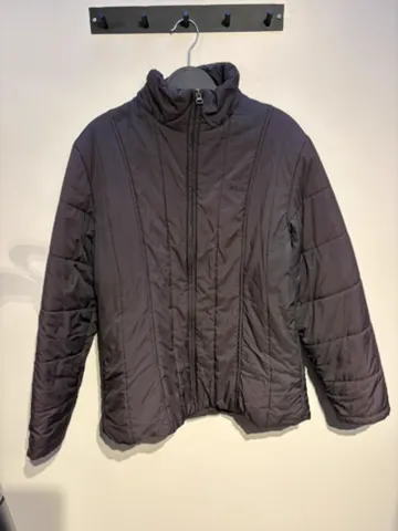The starting photo for the channel-quilted puffer: the quilted puffer on a hanger against a shop wall