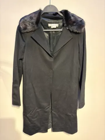 The starting photo for the wool coat with faux-fur collar: the wool coat on a hanger against a shop wall